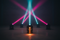 Four compact moving-head light fixtures on concrete warehouse floor casting magenta, cyan and amber beams through stage haze